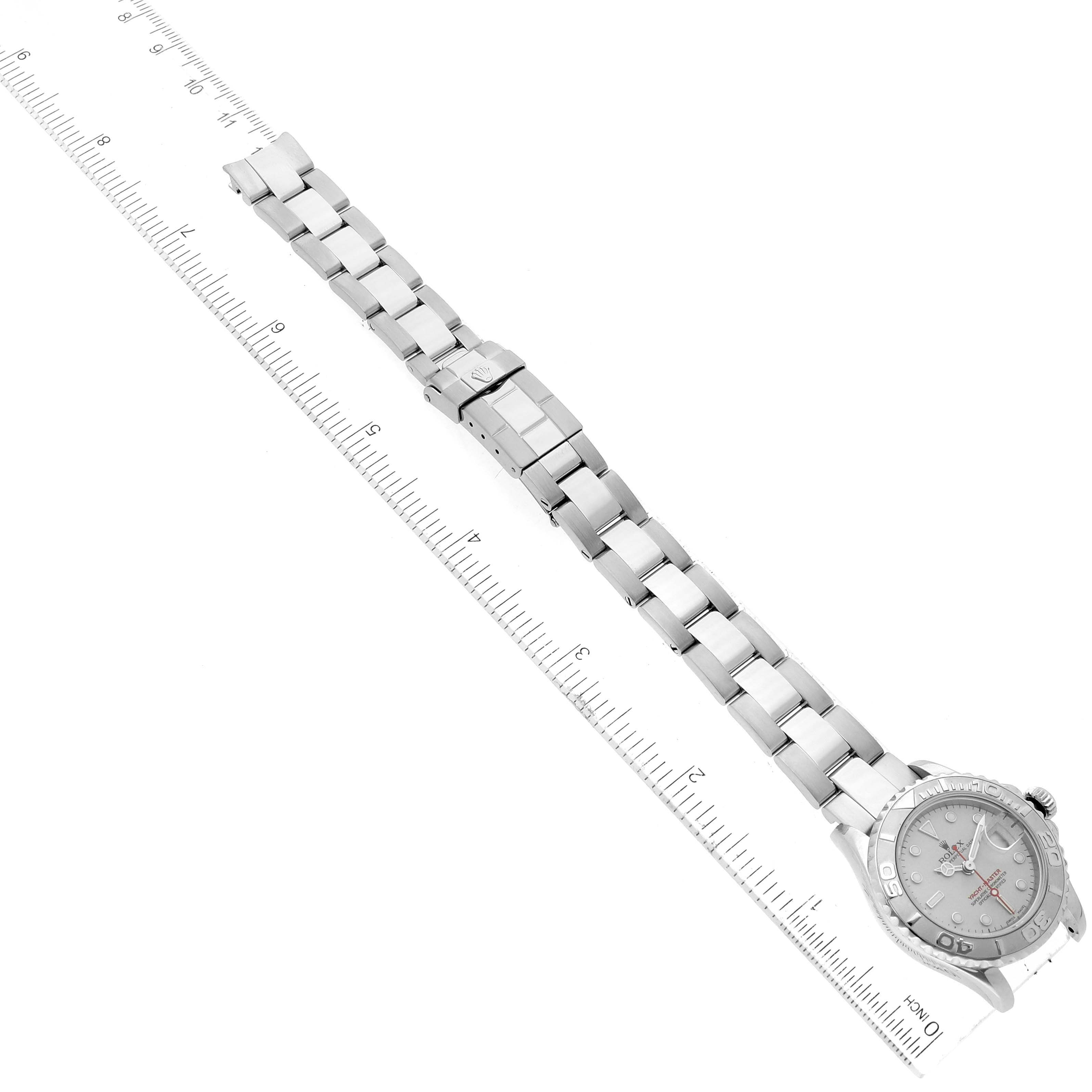 The image shows a Rolex Yacht-Master 169622 Women's Stainless Steel Silver Dial 169622 Women's Stainless Steel Silver Dial watch with its band fully extended, placed along a measuring ruler.