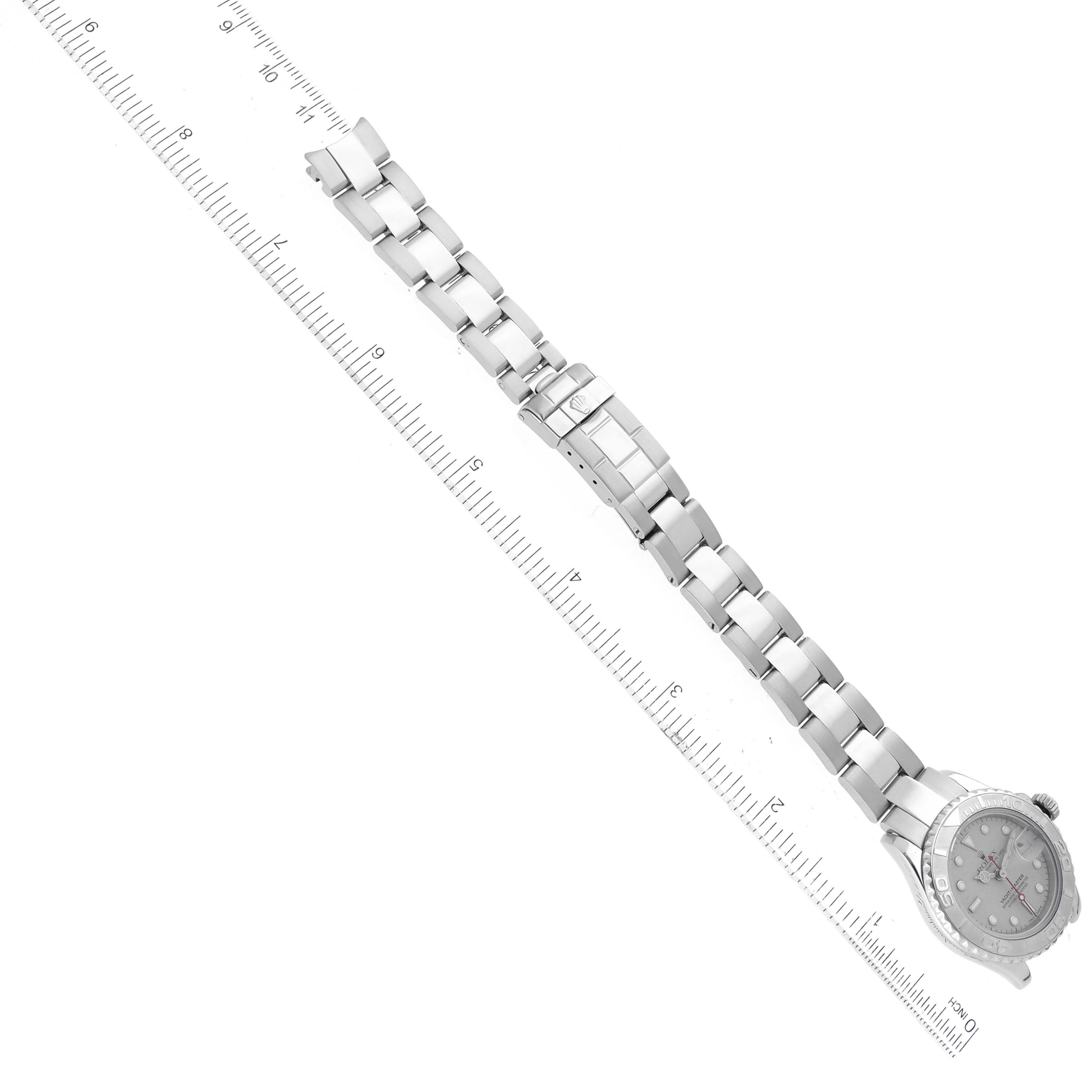 The image shows a top view of a Rolex Yacht-Master 169622 Women's Stainless Steel Silver Dial 169622 Women's Stainless Steel Silver Dial watch and its metal bracelet, aligned with a ruler for scale.