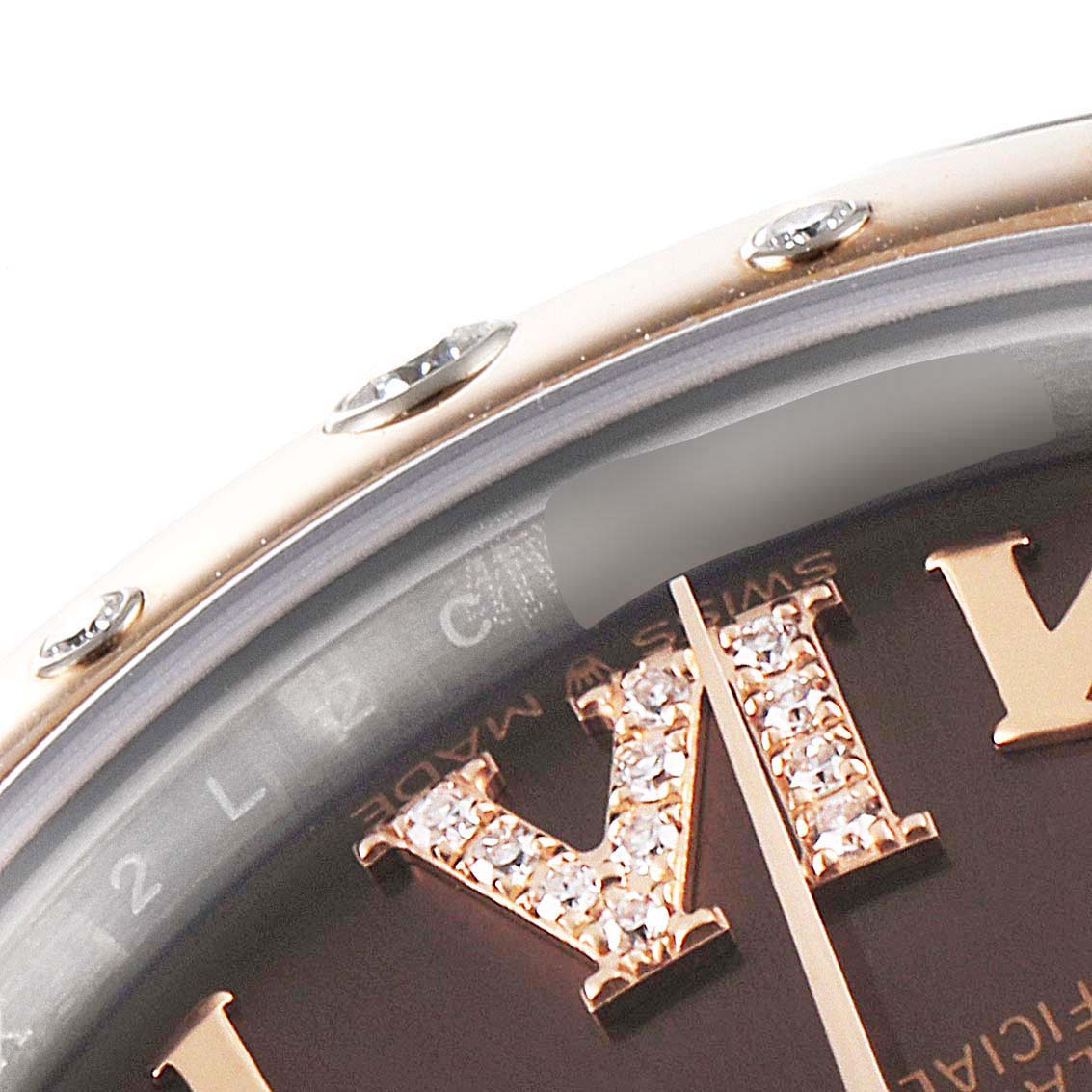 The close-up image shows the upper section of the bezel, dial, and Roman numeral XII of the Mid-Size Rolex watch.
