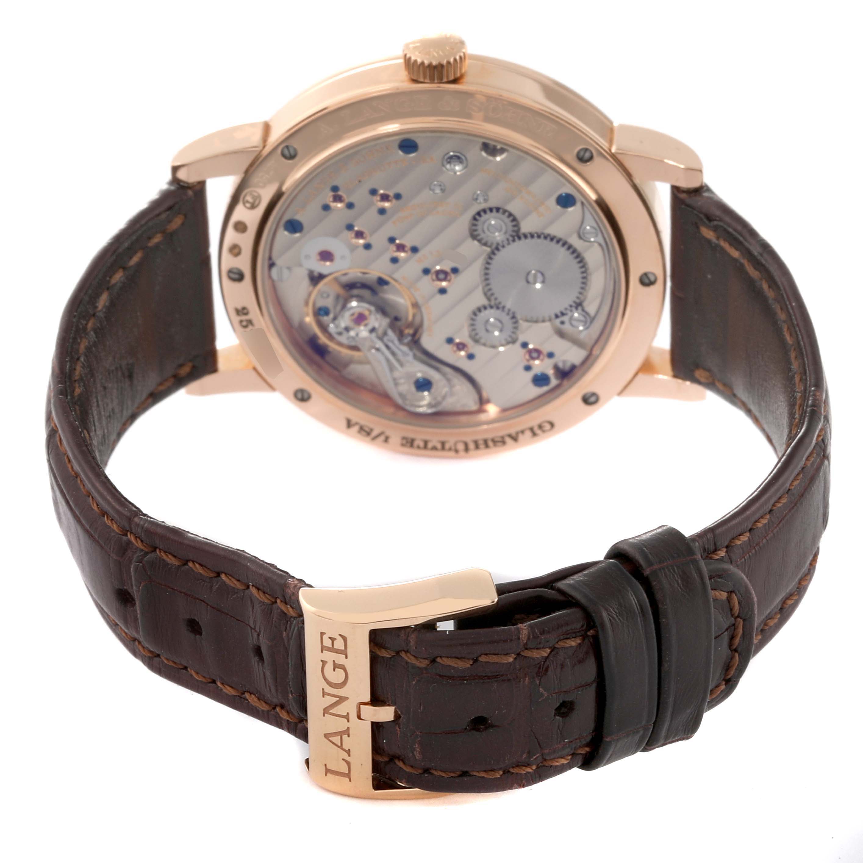 The image shows the back view of an A. Lange & Sohne 1815 234.032 Men's Rose Gold Silver Dial watch, highlighting its movement and leather strap.