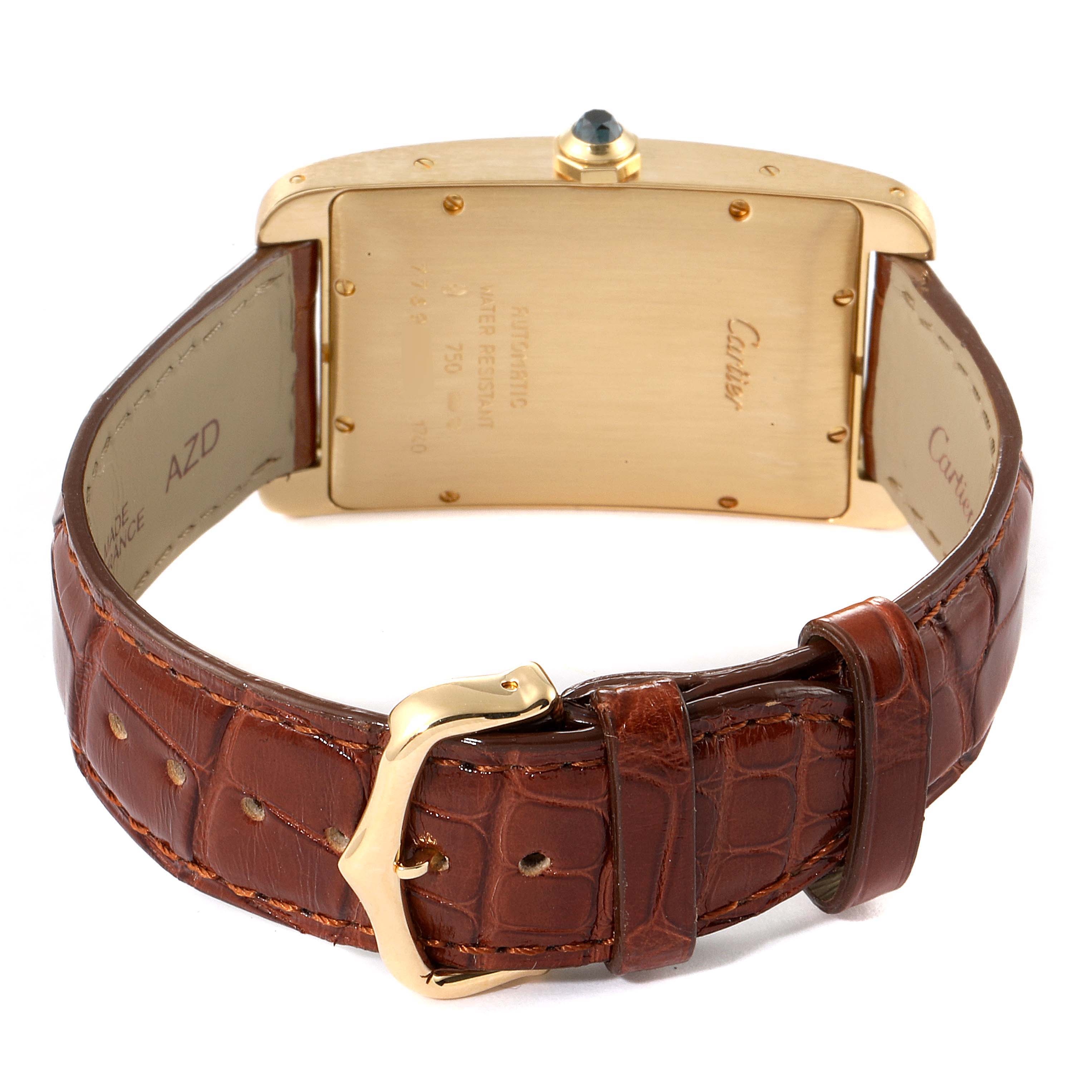 The image shows the back of the Cartier Tank Americaine W2603156 Men's Yellow Gold Silver Dial W2603156 Men's Yellow Gold Silver Dial watch and its brown leather strap and gold buckle.