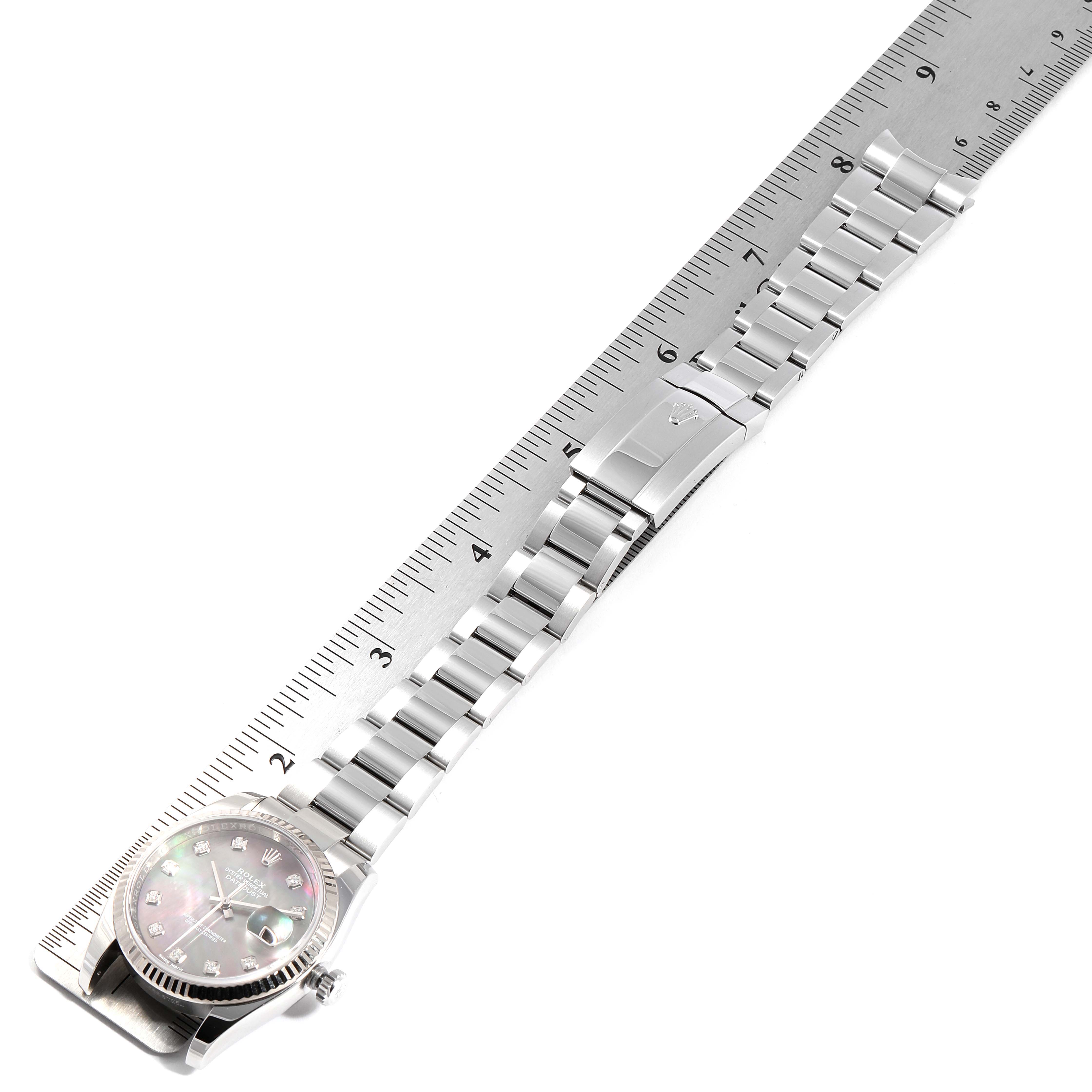 This image shows a Rolex Datejust 116234 Men's Stainless Steel Mother of Pearl Dial 116234 Men's Stainless Steel Mother of Pearl Dial watch set alongside a ruler, displaying the watch face, strap, and clasp.