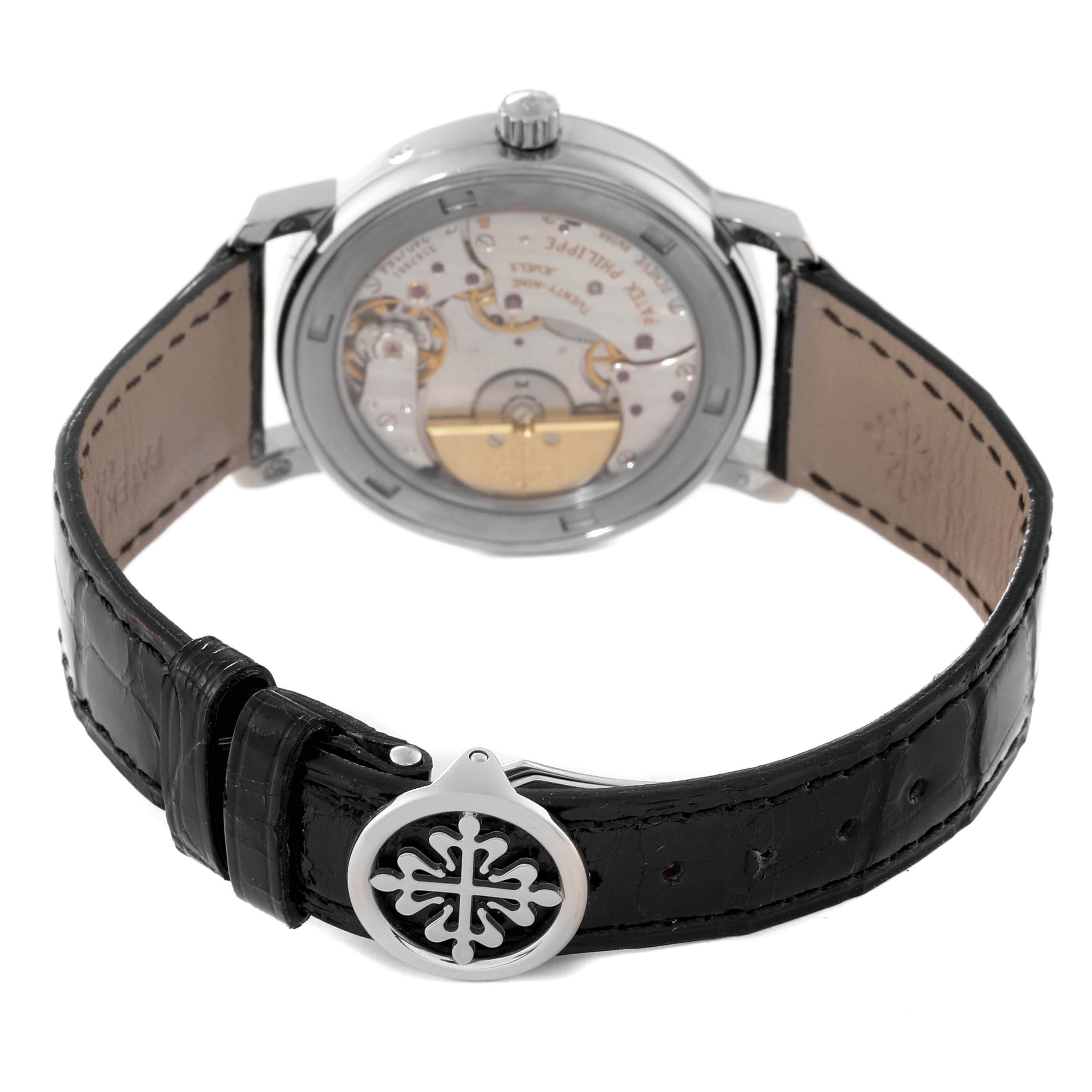 The image shows the back view of a Patek Philippe Complications 5055G-010 Men's White Gold Black Dial 5055G-010 Men's White Gold Black Dial watch, highlighting its movement and leather strap with a decorative clasp.