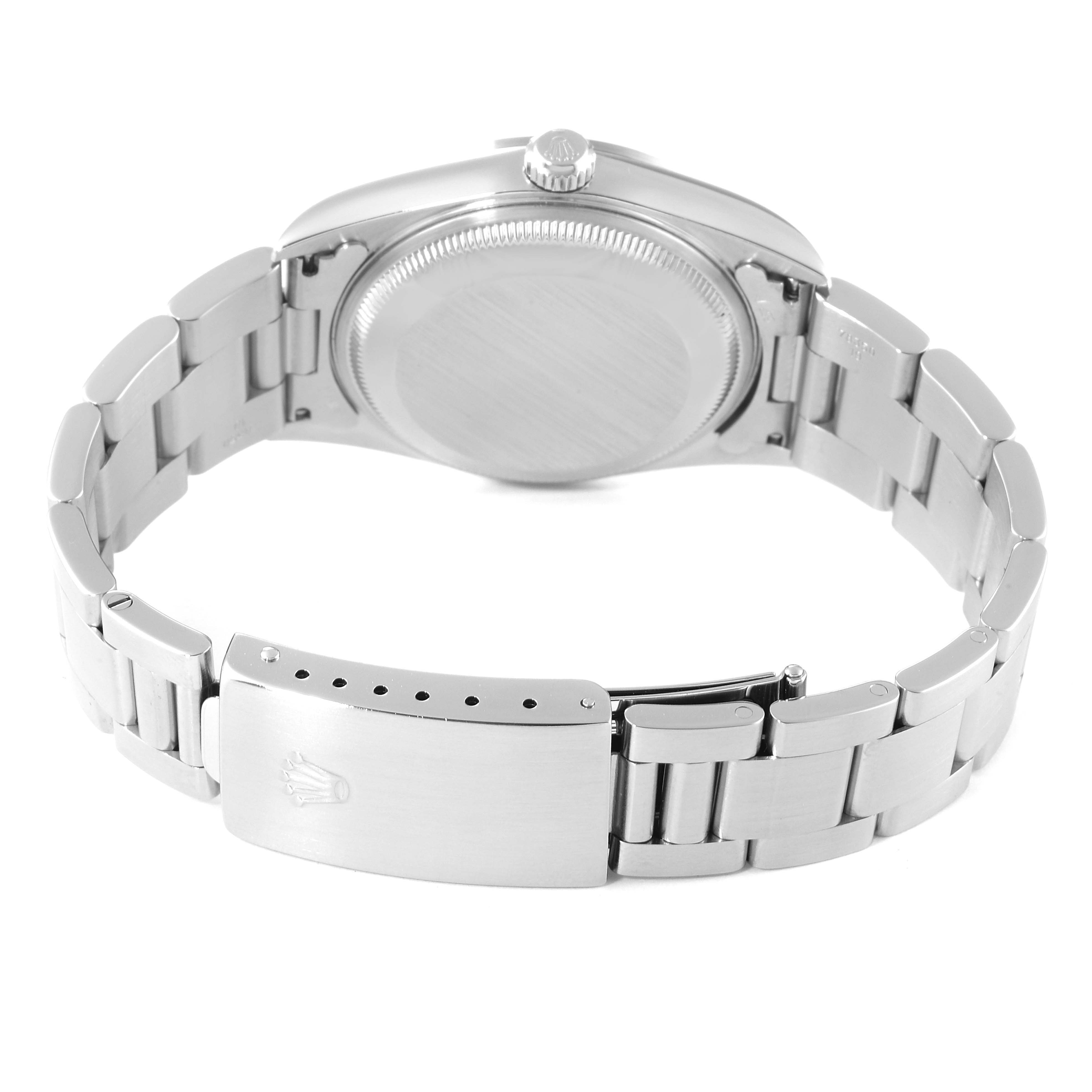 The image shows the back view of a Date model Rolex watch, highlighting its clasp and bracelet.