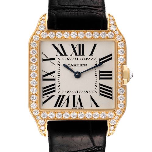 The Cartier Santos Dumont WH100351 Men's Yellow Gold Silver Dial WH100351 Men's Yellow Gold Silver Dial watch is shown from a front view, displaying its diamond-encrusted bezel, Roman numeral dial, and black leather strap.
