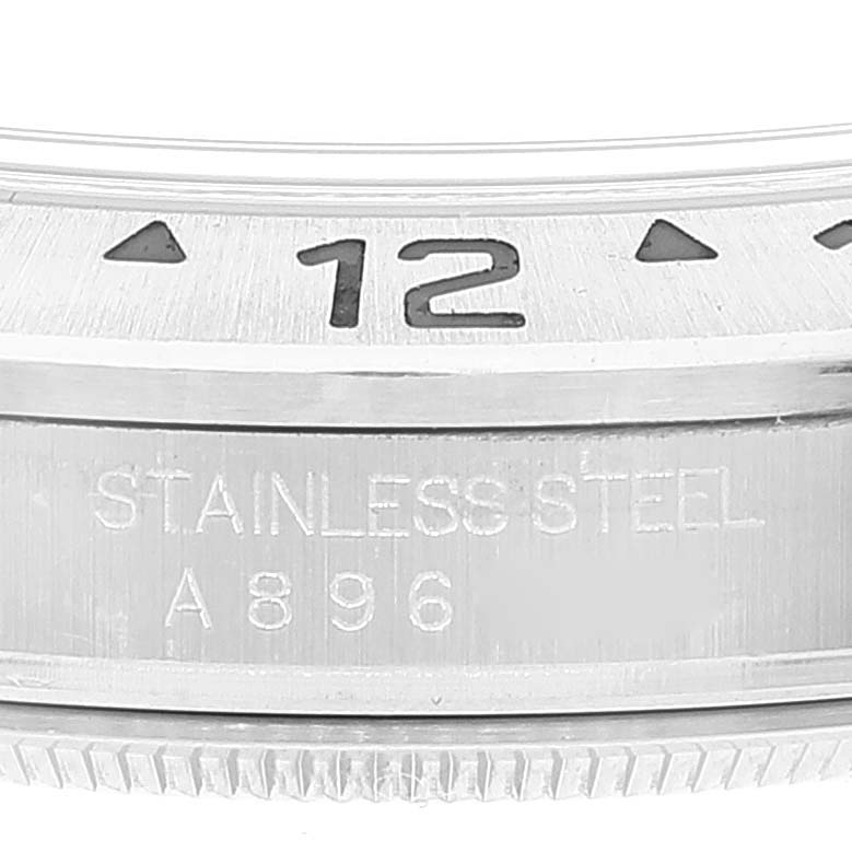 The image shows a close-up of the bezel and case of a Rolex Explorer 16570 Men's Stainless Steel White Dial 16570 Men's Stainless Steel White Dial watch, featuring the 12 o'clock marker and "STAINLESS STEEL" engraving.