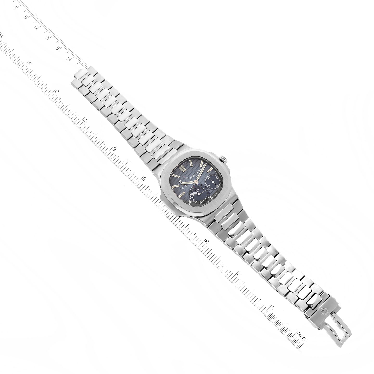 The image shows a Patek Philippe Nautilus 5712/1A-001 Men's Stainless Steel Blue Dial 5712/1A-001 Men's Stainless Steel Blue Dial watch laid flat with its face and stainless steel bracelet fully visible next to a ruler for scale.
