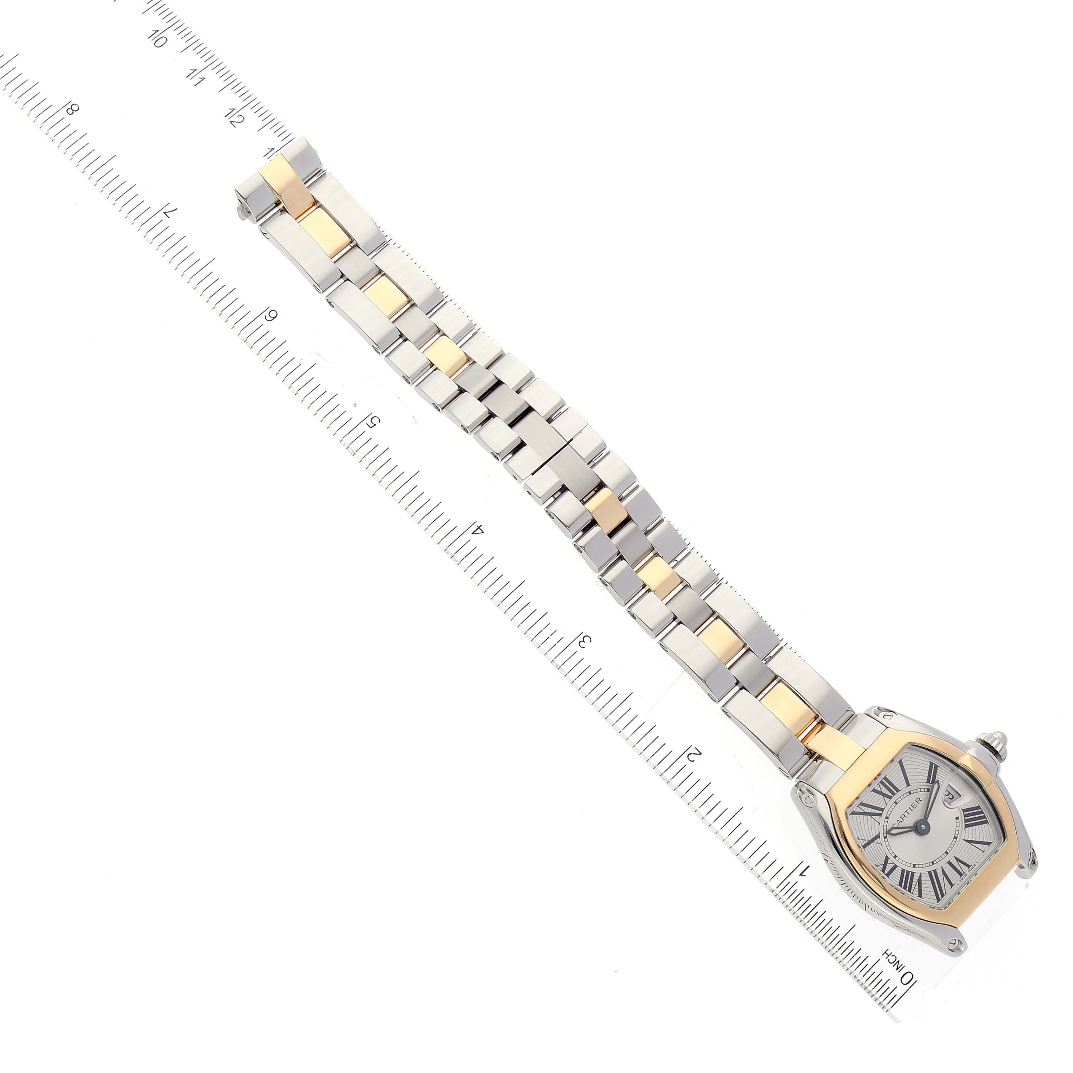 The image shows a top view of the Cartier Roadster W62026Y4 Women's Steel and Gold (two tone) Silver Dial W62026Y4 Women's Steel and Gold (two tone) Silver Dial model watch with a silver and gold-toned bracelet next to a ruler.