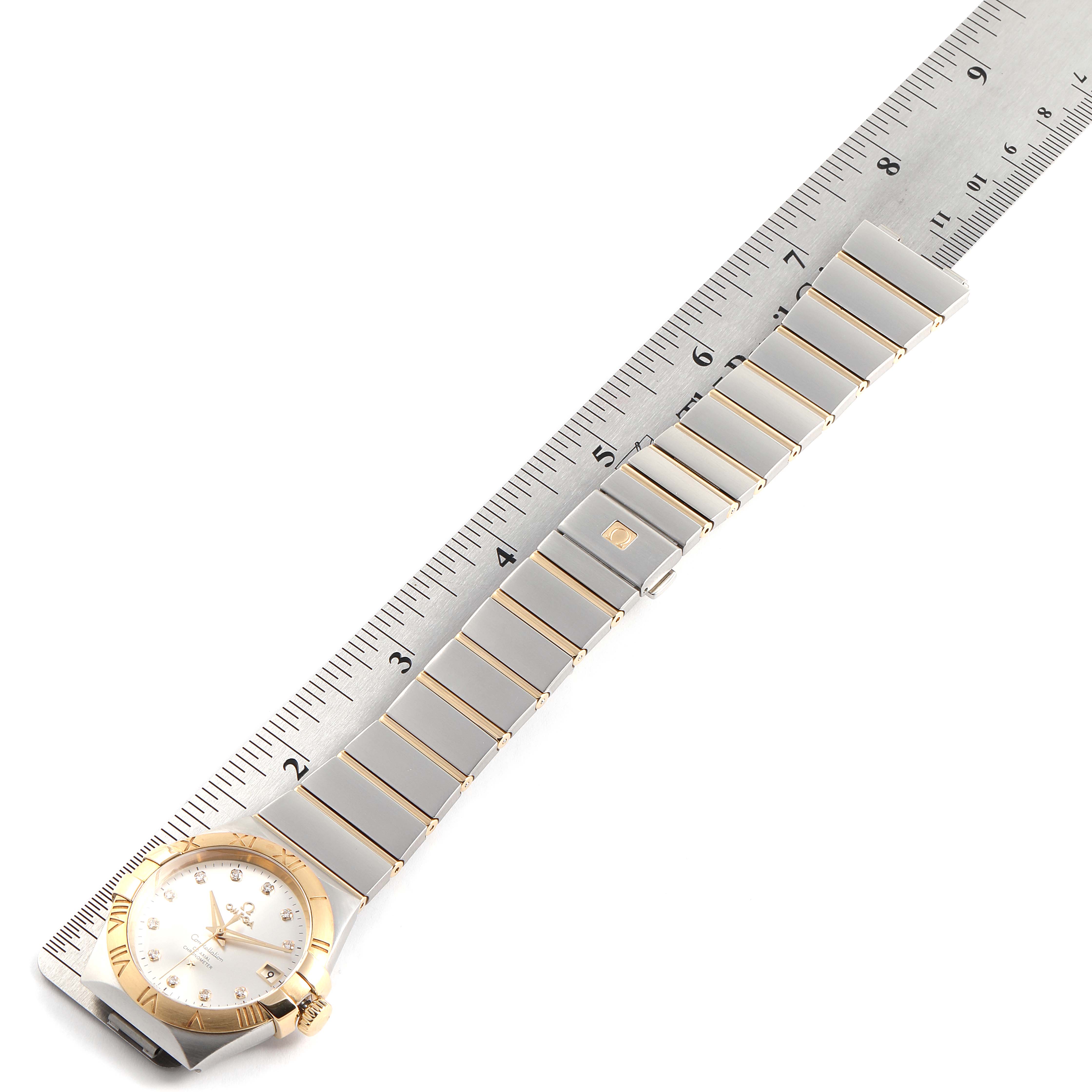 The image shows an Omega Constellation 111.20.36.20.52.001 Men's Steel and Gold (two tone) Silver Dial 111.20.36.20.52.001 Men's Steel and Gold (two tone) Silver Dial watch with its bracelet and dial positioned next to a ruler for size reference.