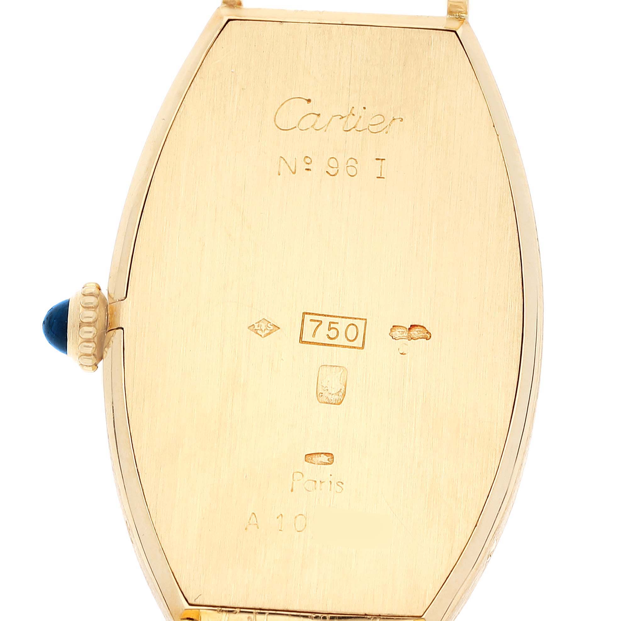 This image shows the back casing of a Cartier Tonneau Women's Yellow Gold Silver Dial Women's Yellow Gold Silver Dial model watch, highlighting its engravings and crown with a blue gemstone.