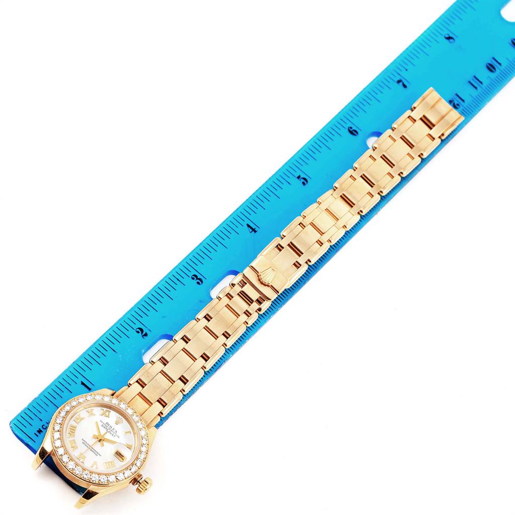 The Rolex Pearlmaster 69298 Women's Yellow Gold Mother of Pearl Dial 69298 Women's Yellow Gold Mother of Pearl Dial watch is shown from a top-down angle, displaying its face, bezel, and bracelet alongside a ruler.